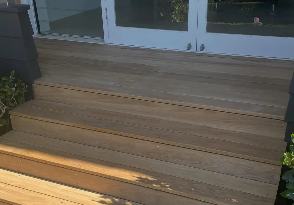 A brand new, beautifully crafted timber deck and matching staircase with clean lines and a pristine finish.